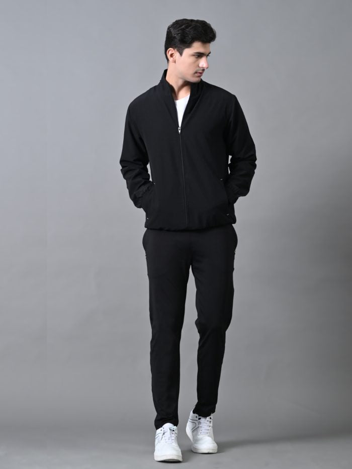 A man wearing a black winter tracksuit with a jacket and joggers